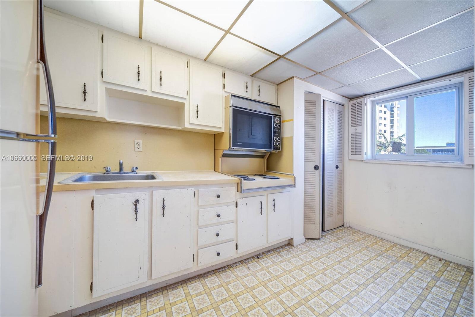 1674 Bay Road, Unit 403 Miami Beach, FL 33139 - Photo 6 of 23 a kitchen with granite countertop white cabinets stainless steel appliances and a window