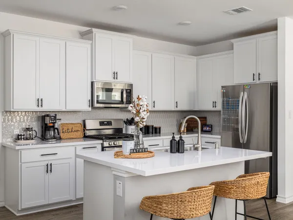 a kitchen with stainless steel appliances granite countertop a stove a sink a refrigerator a dining table and chairs