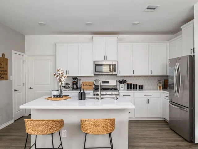 a kitchen with stainless steel appliances a sink a stove a refrigerator cabinets and dining table