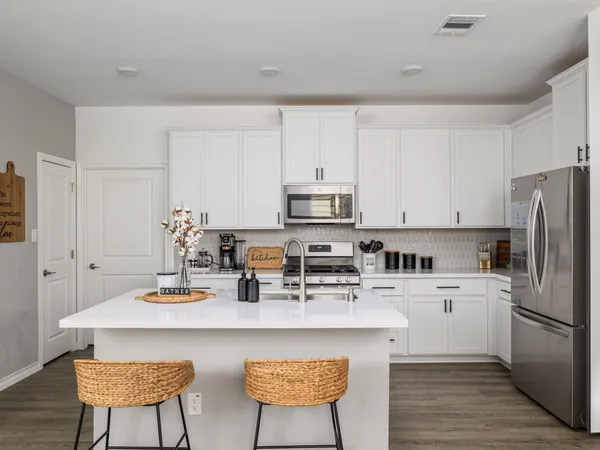 a kitchen with stainless steel appliances a sink a stove a refrigerator cabinets and dining table