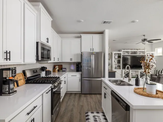 a kitchen with a refrigerator a sink a stove a microwave and wooden cabinets