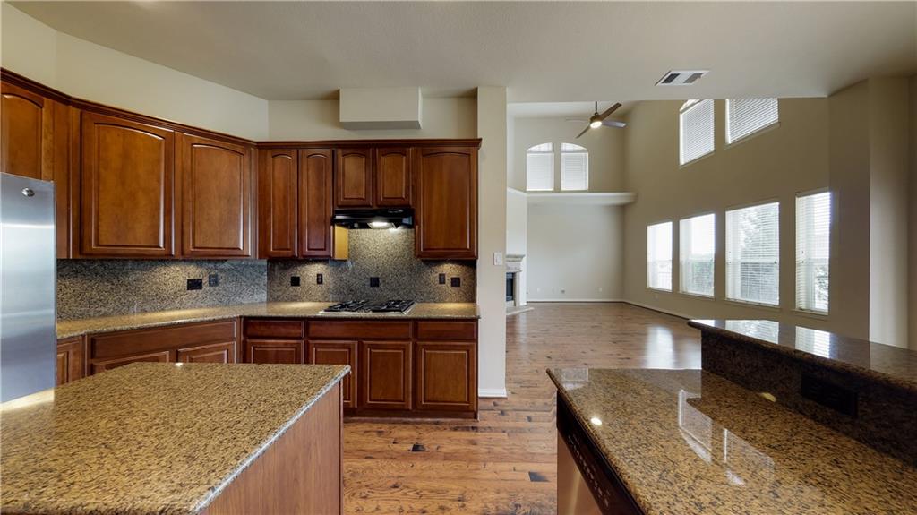 7136 Playa Grand Prairie, TX 75054 - Photo 22 of 36 a kitchen with kitchen island granite countertop wooden cabinets a sink and dishwasher