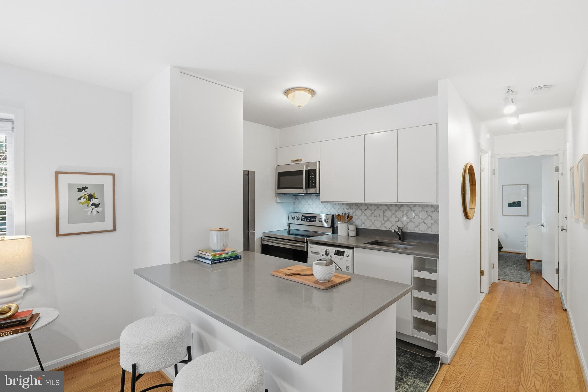 1833-1855 Biltmore Street Northwest, Unit A Washington, DC 20009 - Photo 10 of 22 a kitchen with stainless steel appliances granite countertop a sink a stove a refrigerator cabinets and a dining table