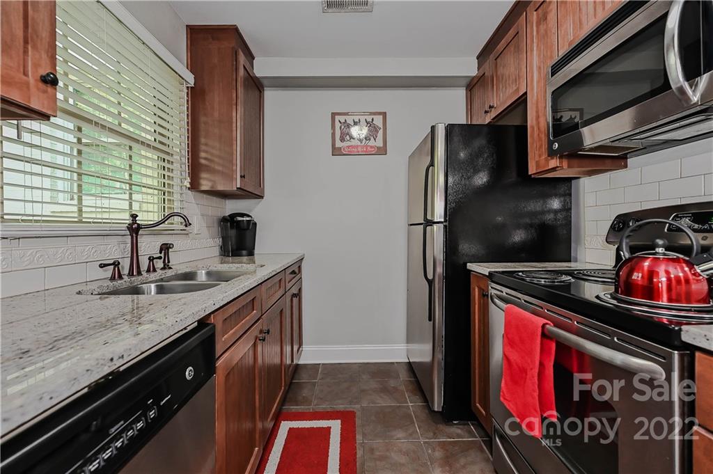 4919 Park Road, Unit D Charlotte, NC 28209 - Photo 10 of 27 a kitchen with stainless steel appliances granite countertop a stove a sink and a microwave
