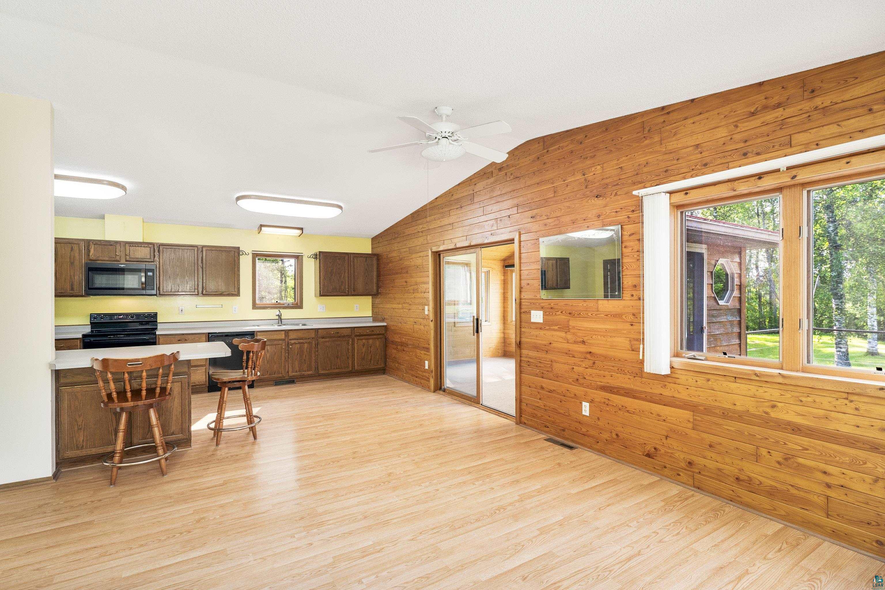 5410 Lavaque Road Duluth, MN 55803 - Photo 18 of 48 Kitchen featuring light hardwood / wood-style flooring, wooden walls, ceiling fan, black appliances, and vaulted ceiling