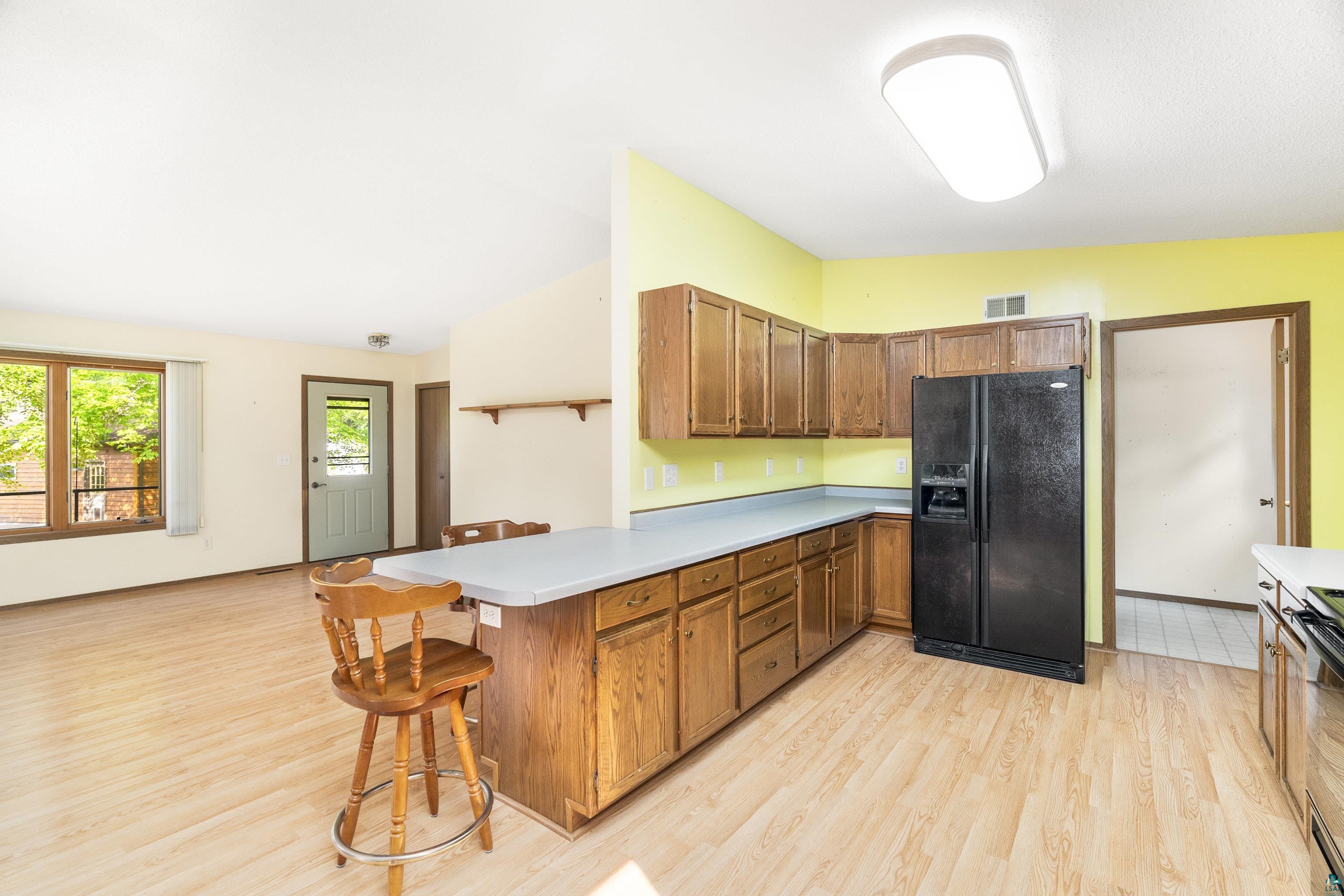 5410 Lavaque Road Duluth, MN 55803 - Photo 10 of 48 Kitchen with light wood-type flooring, a breakfast bar area, black fridge with ice dispenser, and lofted ceiling