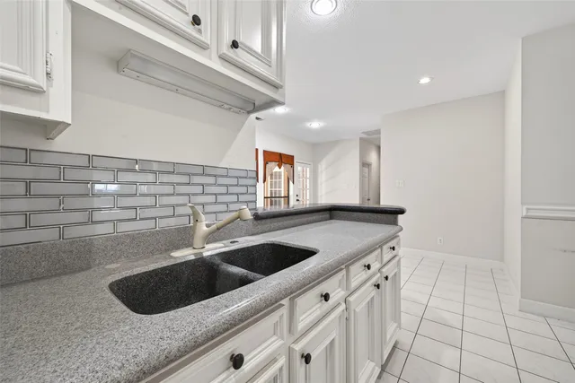 a kitchen with granite countertop white cabinets and stainless steel appliances