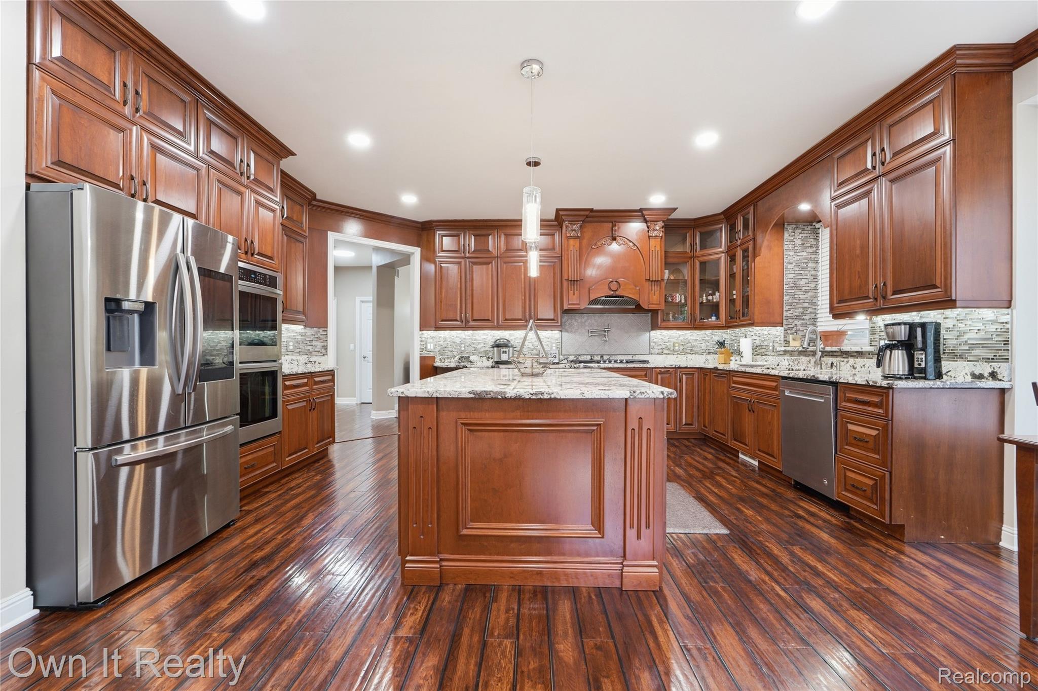 48280 Gladstone Road Canton, MI 48188 - Photo 15 of 59 Spacious kitchen featuring rich wood cabinetry, stainless steel appliances, a central island with a stone countertop, a decorative backsplash, and recessed lighting