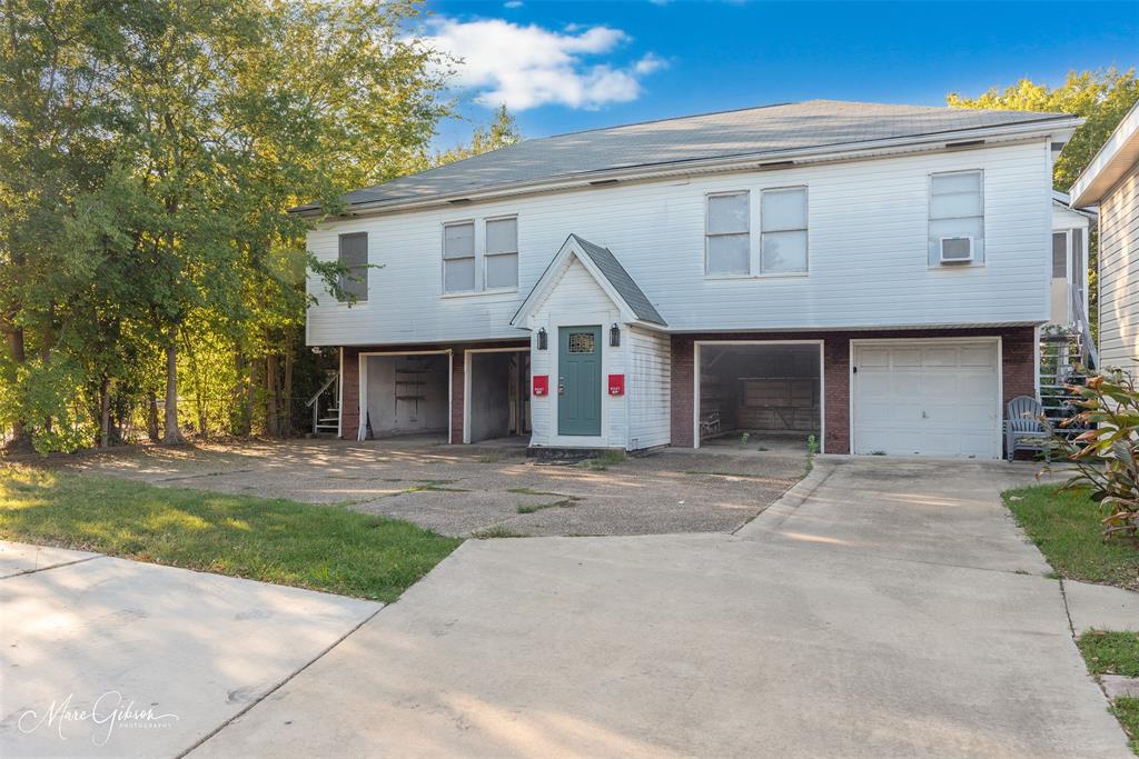 a view of a white house with a large space next to a yard