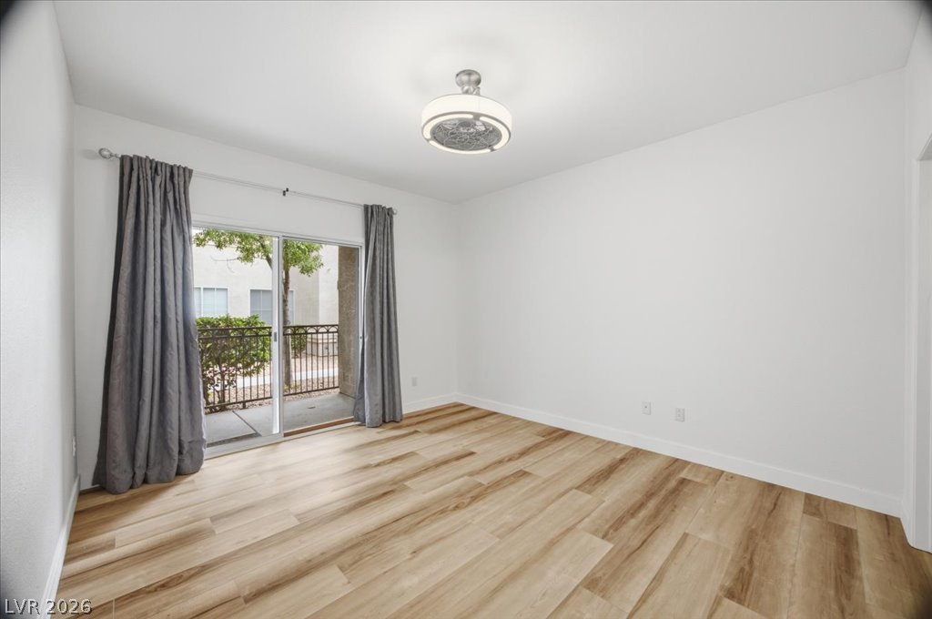 9050 West Warm Springs Road, Unit 1033 Las Vegas, NV 89148 - Photo 9 of 26 Hardwood-style flooring and a sliding glass door opening to an outdoor balcony elevate this bright living space.