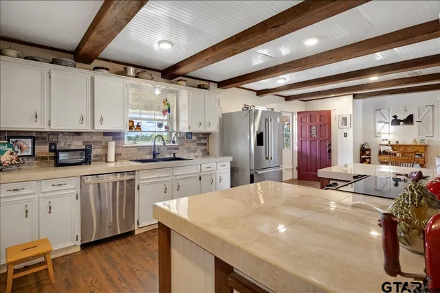 a kitchen with stainless steel appliances kitchen island granite countertop a table chairs sink and cabinets