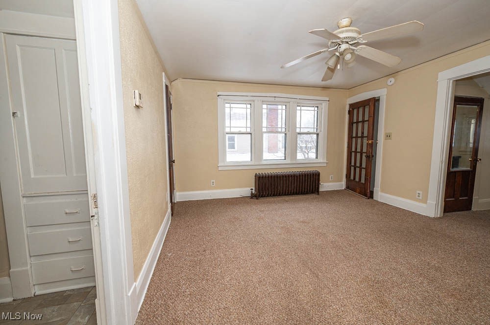 3114 Neosho Road Youngstown, OH 44511 - Photo 11 of 25 Empty room with radiator heating unit, ceiling fan, and carpet floors
