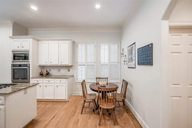 a kitchen with stainless steel appliances a dining table chairs and a refrigerator