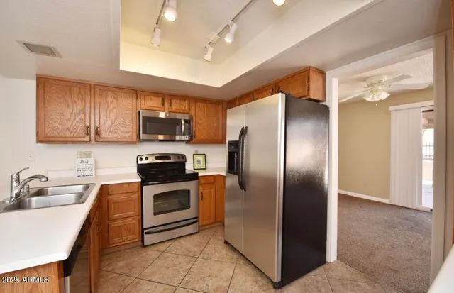 a kitchen with stainless steel appliances granite countertop a refrigerator a sink a stove top oven and a center island