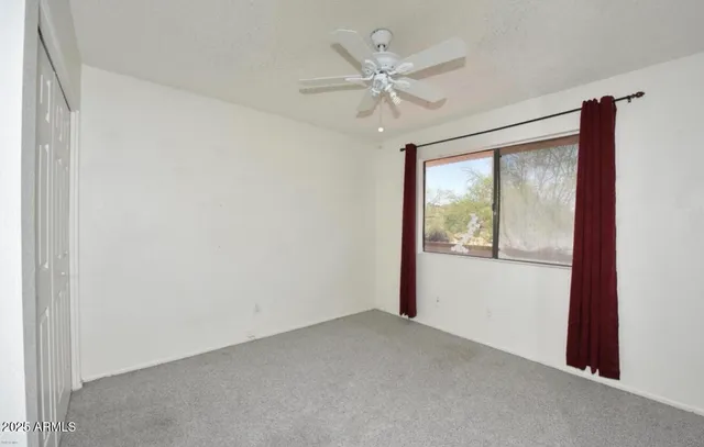 an empty room with a window and a fan
