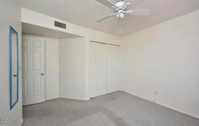 an empty room with a ceiling fan and a window