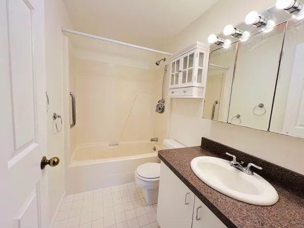 a bathroom with a granite countertop sink a toilet a mirror and shower