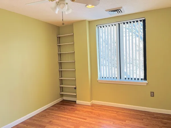 an empty room with a windows and chandelier fan