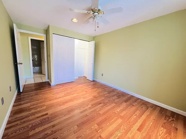wooden floor in an empty room with a chandelier fan