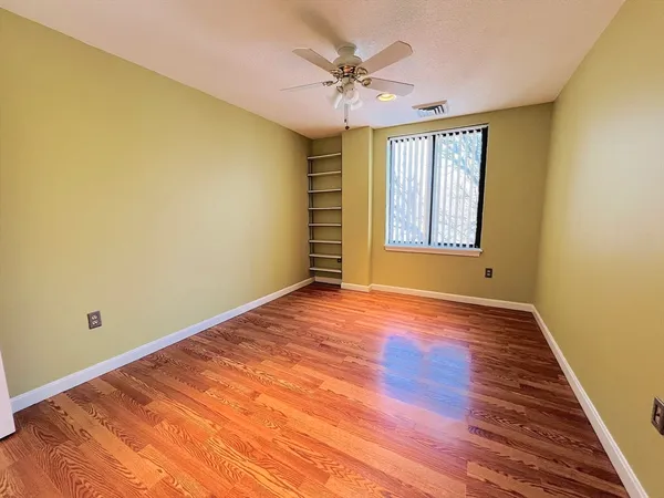 a view of an empty room with a window and wooden floor