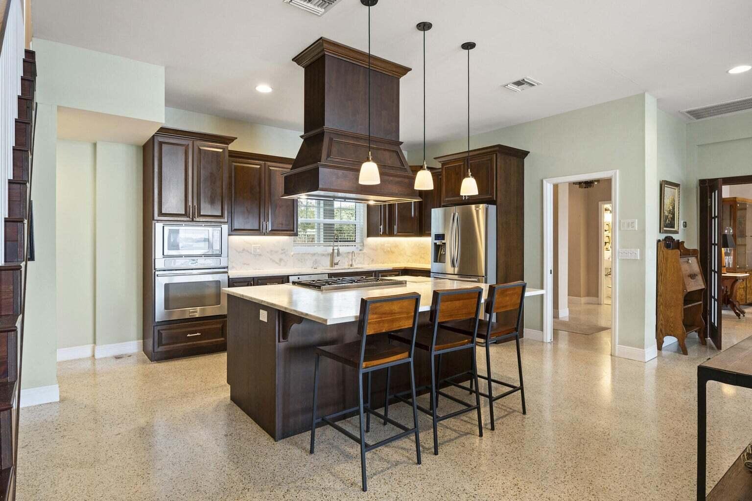 1009 Northwest Terrace Road Stuart, FL 34994 - Photo 15 of 69 a kitchen with stainless steel appliances kitchen island granite countertop a refrigerator a stove a sink a dining table and chairs with wooden floor