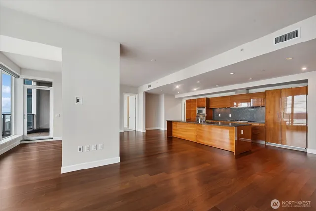 a view of an empty room with wooden floor and a window