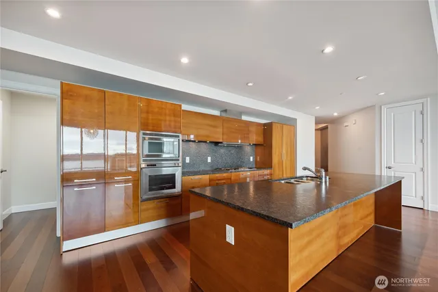 a kitchen with stainless steel appliances granite countertop a sink a stove and a wooden cabinets