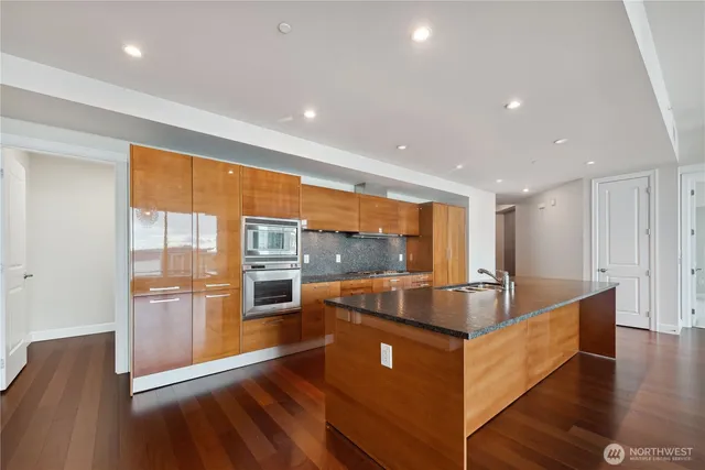 a large kitchen with stainless steel appliances a large counter top and a wooden floors