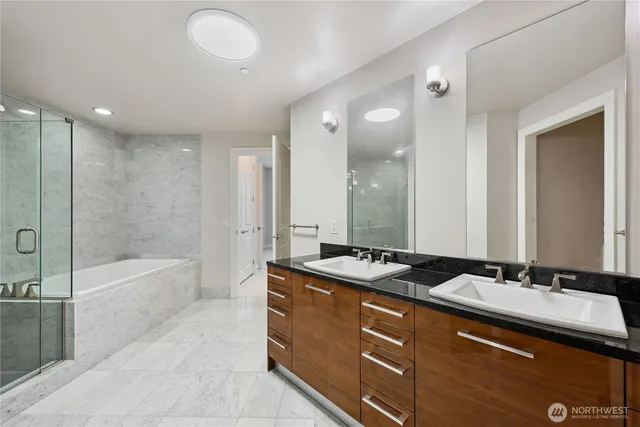 a bathroom with a sink double vanity granite tub shower and a mirror