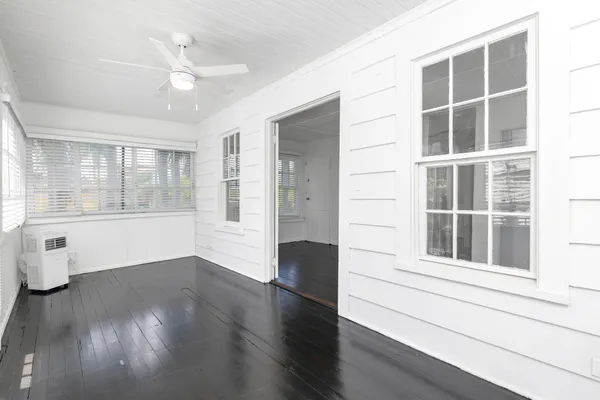 a view of an empty room with a window and wooden floor