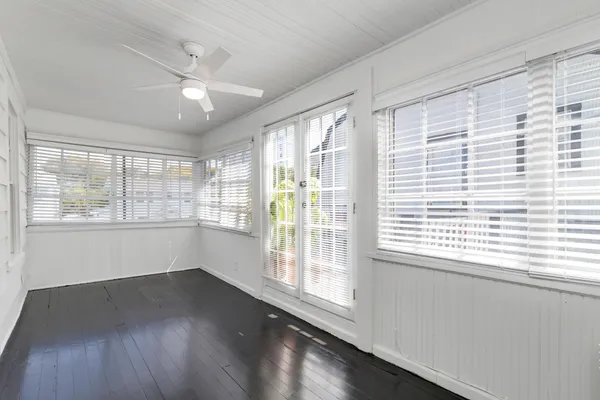 a view of an empty room with wooden floor and a window
