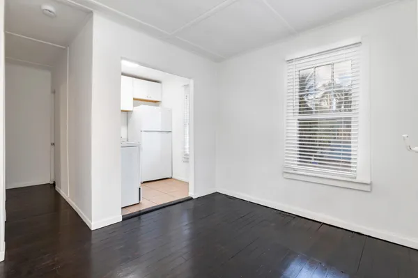 an empty room with wooden floor closet and windows