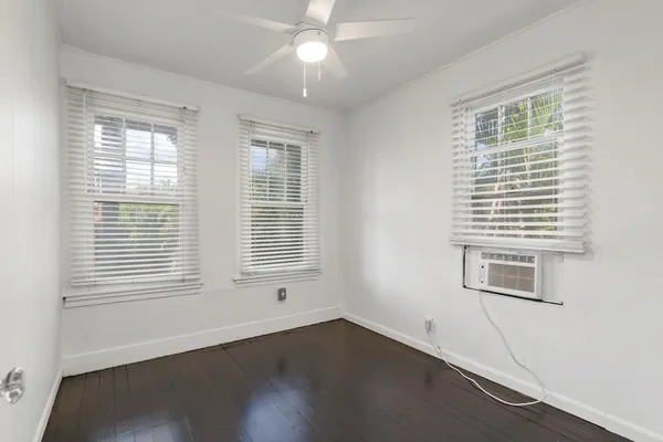 a view of an empty room with wooden floor and a window