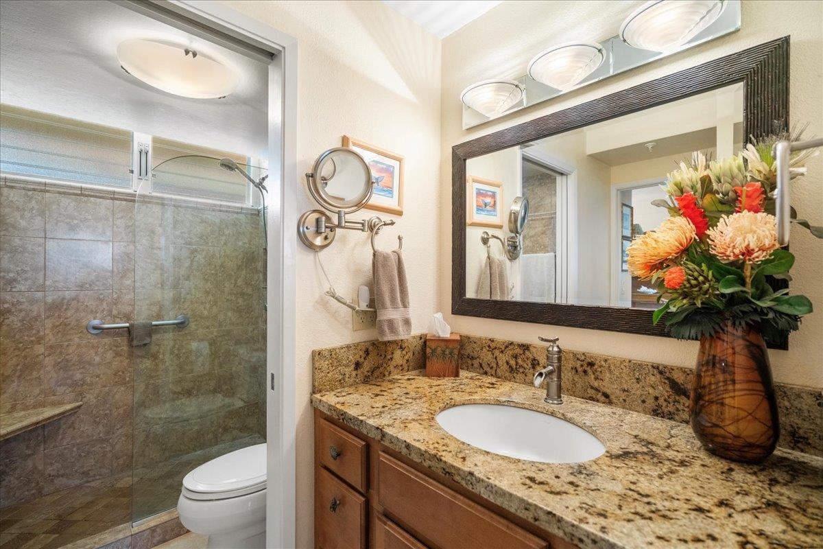 4365 Lower Honoapiilani Road, Unit 907 Lahaina, HI 96761 - Photo 16 of 23 a bathroom with a granite countertop sink a toilet and a mirror