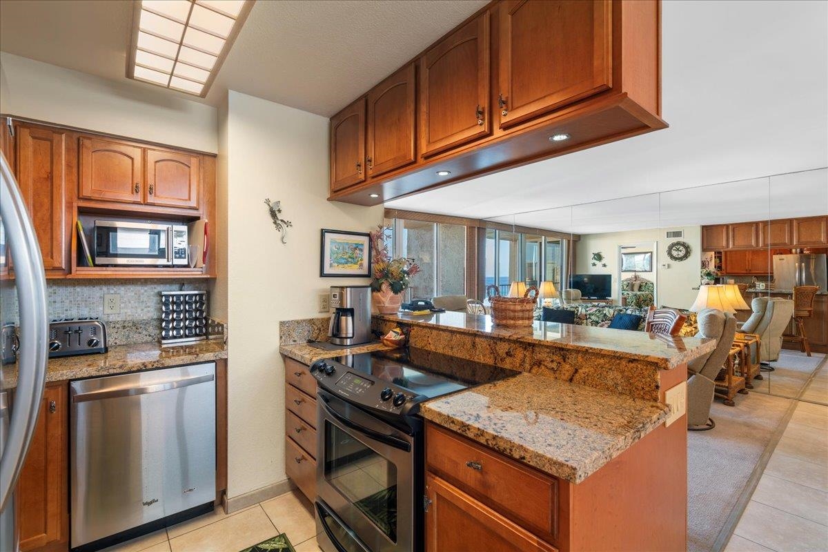 4365 Lower Honoapiilani Road, Unit 907 Lahaina, HI 96761 - Photo 8 of 23 a kitchen with stainless steel appliances granite countertop a stove refrigerator and cabinets