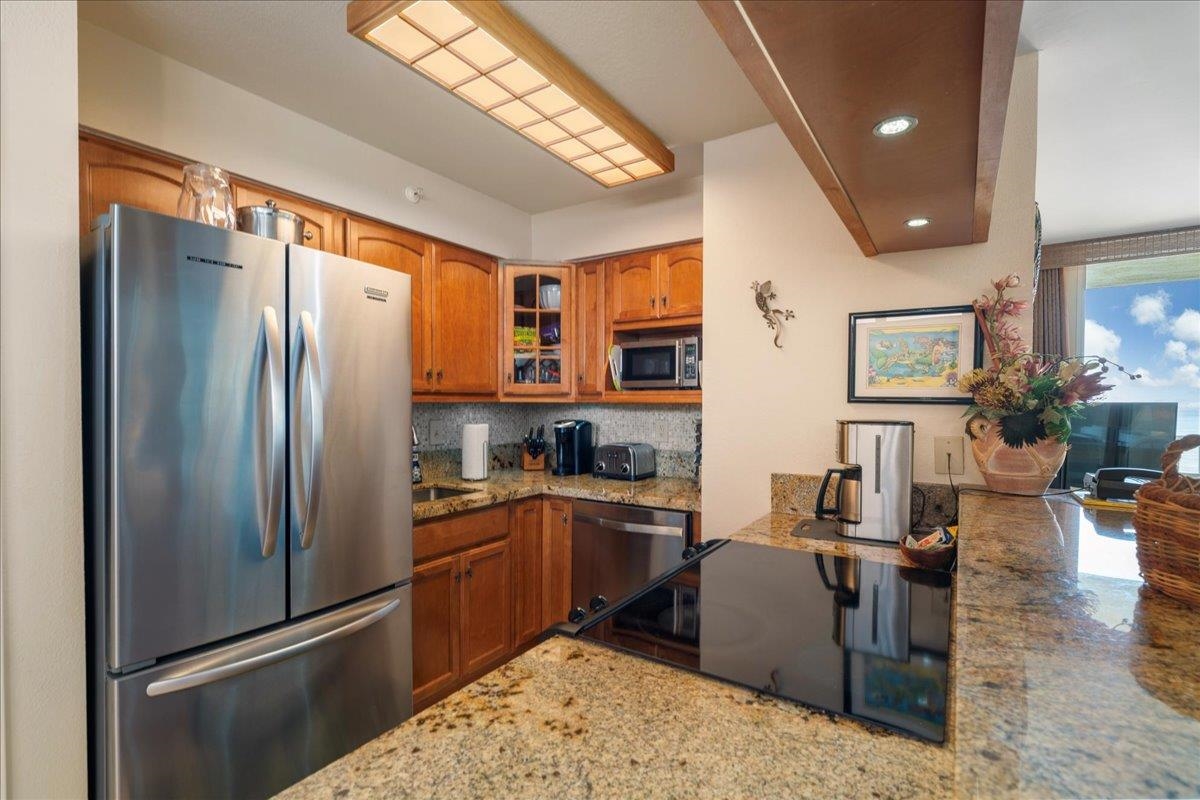 4365 Lower Honoapiilani Road, Unit 907 Lahaina, HI 96761 - Photo 9 of 23 a kitchen with stainless steel appliances granite countertop a refrigerator a sink a stove and island