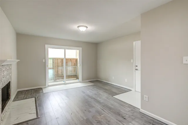 an empty room with wooden floor fireplace and windows