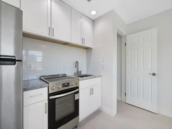 a kitchen with stainless steel appliances granite countertop a stove and a white cabinets
