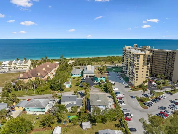 an aerial view of ocean and residential houses with outdoor space