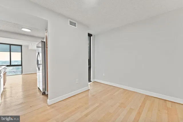 an empty room with wooden floor and windows