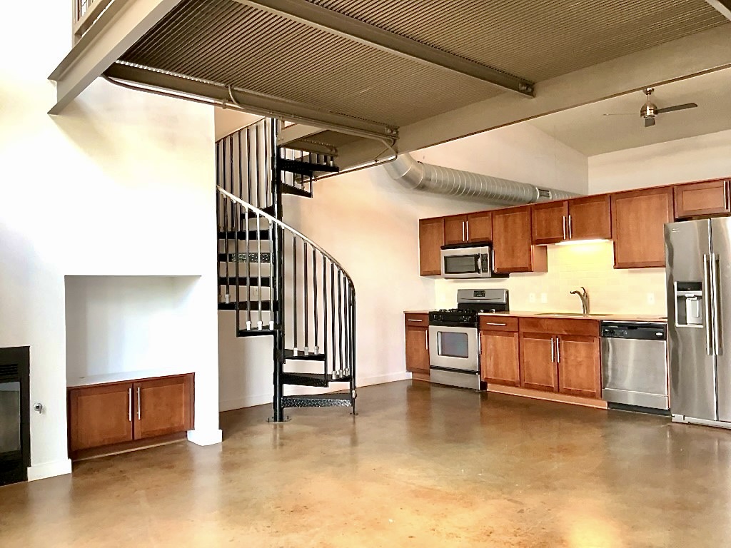 1601 East Cesar Chavez Street, Unit 306 Austin, TX 78702 - Photo 4 of 19 a kitchen with stainless steel appliances kitchen island granite countertop a refrigerator and stove