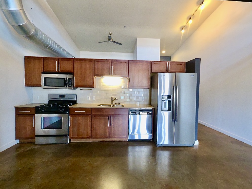 1601 East Cesar Chavez Street, Unit 306 Austin, TX 78702 - Photo 5 of 19 a kitchen with granite countertop a refrigerator and a stove top oven