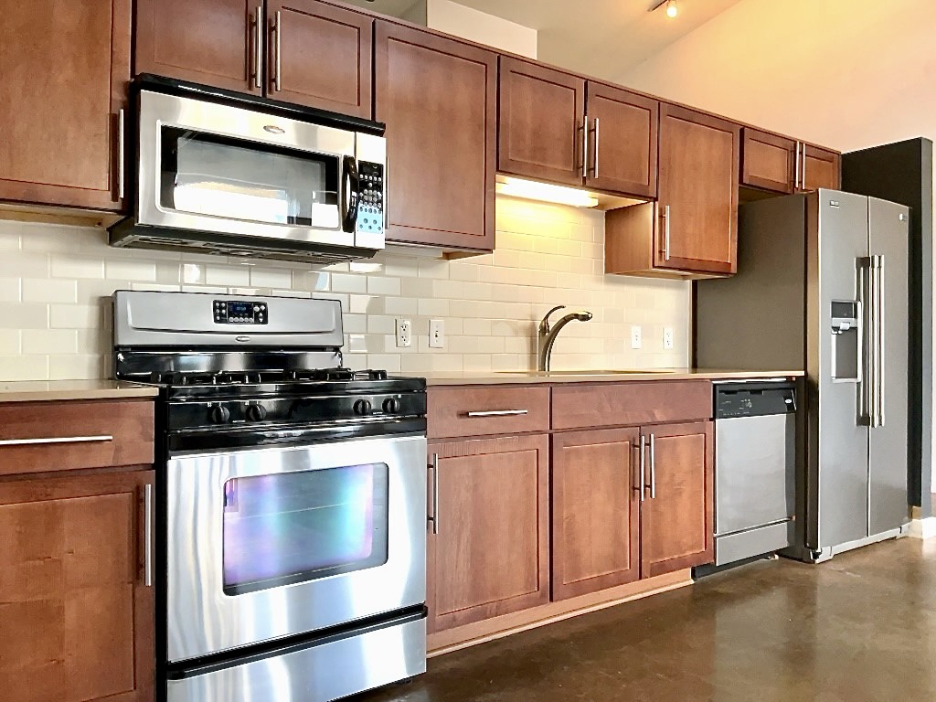 1601 East Cesar Chavez Street, Unit 306 Austin, TX 78702 - Photo 6 of 19 a kitchen with stainless steel appliances wooden cabinets and a stove top oven