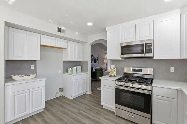 a kitchen with stainless steel appliances white cabinets and stove top oven