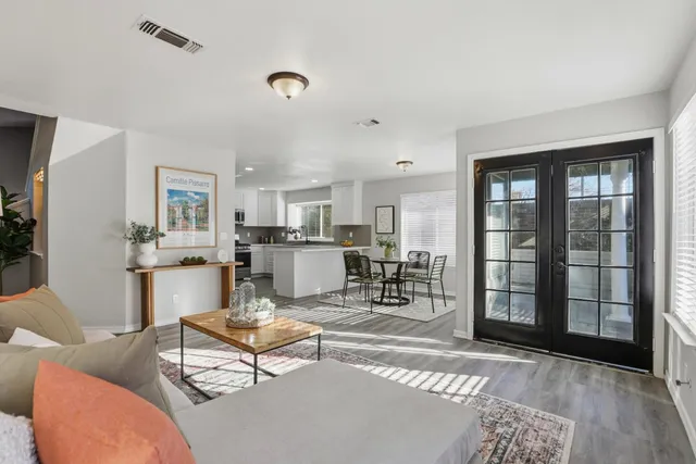 a living room with furniture a rug kitchen view and a large window