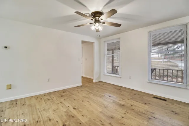 a view of an empty room with a chandelier fan