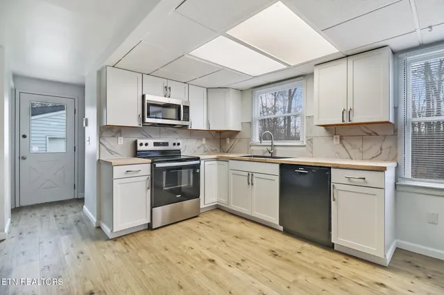 a kitchen with granite countertop a sink cabinets and stainless steel appliances
