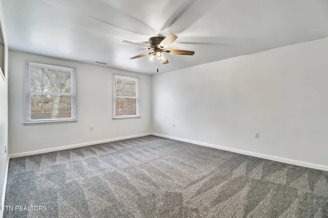an empty room with windows and fan
