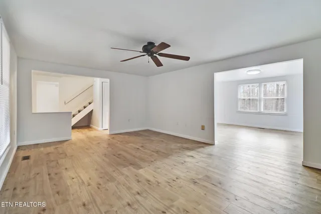 a view of empty room with wooden floor and fan
