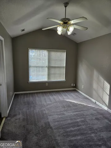 an empty room with a chandelier fan and windows